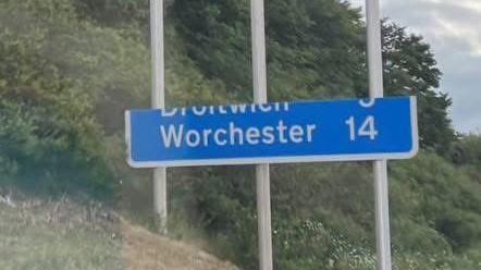 A partially complete blue motorway sign. The sign reads "Worchester" and states that the city is 14 miles away.