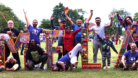 A group of people using celebratory gestures in front of waist-high letters spelling MELA