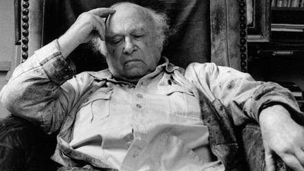 Josef Herman sitting and chair with his hand on his forehead and eyes closed, seemingly deep in thought