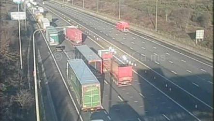 Lorries and cars queuing on one side of the motorway. The opposite carriageway is empty, apart from a van and a car