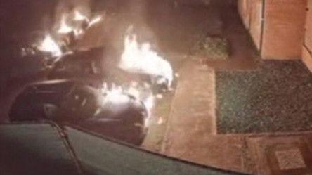 A CCTV image of five cars on fire outside a row of houses.