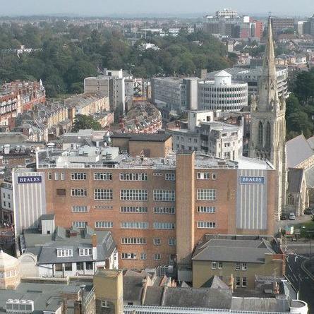 An aerial view of the large red brick Beales building with Bournemouth town centre behind.