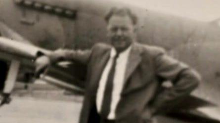 An old photograph of the father. He is wearing a suit and appears to be in front of a plane. 