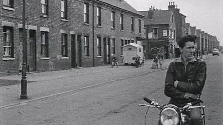 Still of a Nottingham street with a man standing with a motorbike