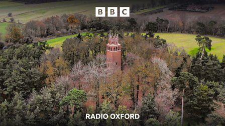 An aerial view of a red brick tower surrounded by trees and fields.