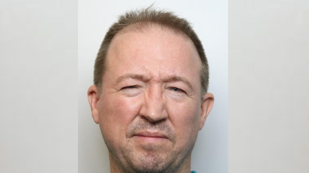 Man with stubble and short brown hair looking directly at the camera with his eyes squinted