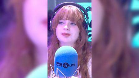 Teenager Evie on BBC Radio 5 Live wearing headphones and listening to someone speak while next to a BBC branded microphone