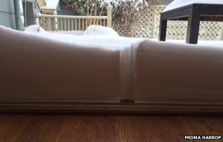 Snow piles up against a glass window in Providence, Rhode Island.