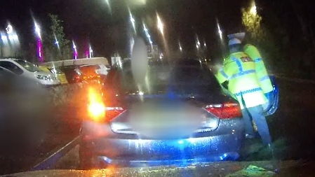 Dealbh dash-cam a' sealltainn càr a' dèanamh às agus a' slaodadh dithis oifigearan poilis leis