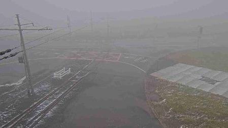 The remains of some snow on the ground at the tram crossing at the Bungalow on the A18. It is foggy and visibility is poor.