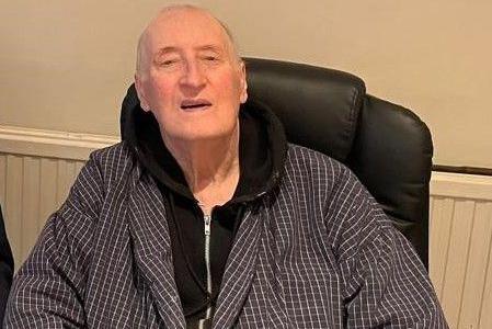 Andrew Farmer in a chair, wearing a black hoodie and checked addressing gown