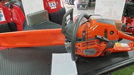 An orange chainsaw with grey handles laying on a table.