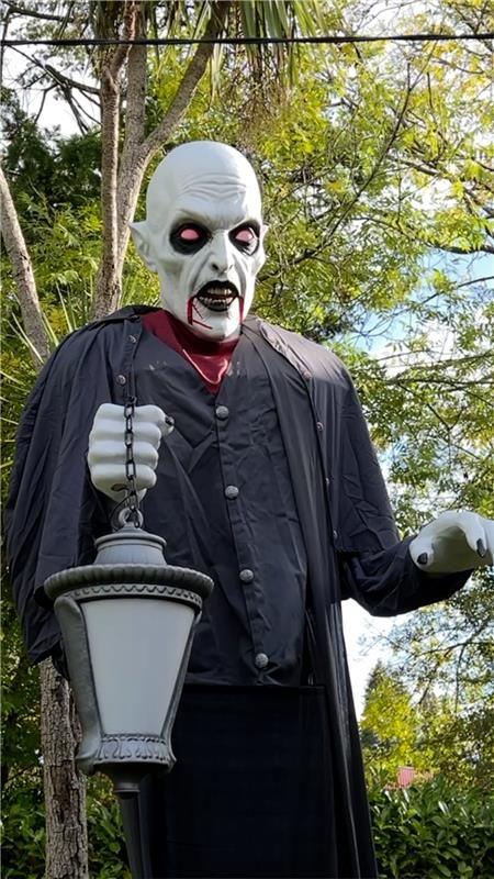 A ghostly figurine dressed in all black holding a lantern.