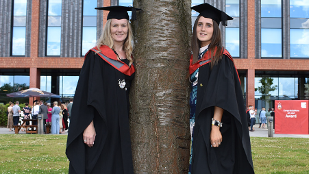 Zoe Tett and Georgia Boote standing by a tree on the day they graduated