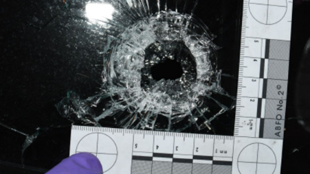 Shattered glass is measured to scale by a police officer after Betro fired a gun at the house which went through windows at the home