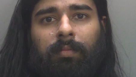 Custody image of Hari Mann. He has a black beard and long black hair