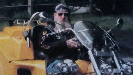 Thomas Edgar wearing a bandana and sunglasses sitting on a motorcycle