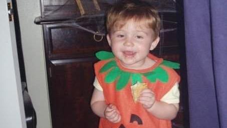 A family photo of Ellis as a Toddler dressed in a Pumpkin costume