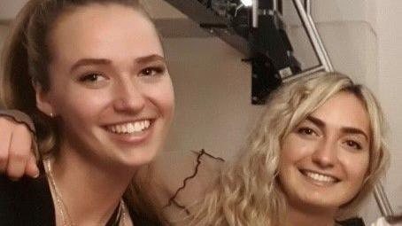 Two women - one with a light brown ponytail and the other with long curly blonde hair.