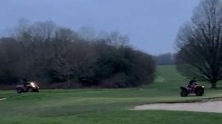 A screen grab of a video of two quad bikes driving around a golf course 