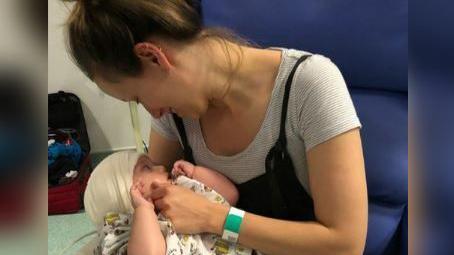 Rory with a bandage around his head being held by mum Amy