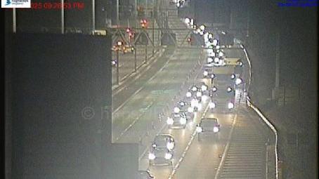 Long tailbacks of cars and lorries on two lanes of the M4 at junction 19 westbound, towards the slip road for the M5. The vehicles all have headlights on. The middle two lanes are empty.