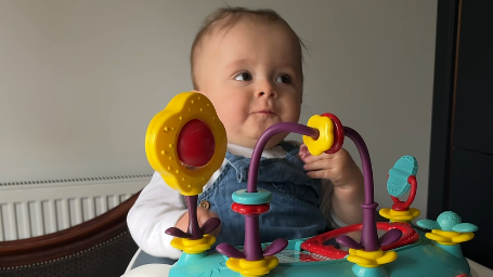 Baby sitting in high chair with toys around