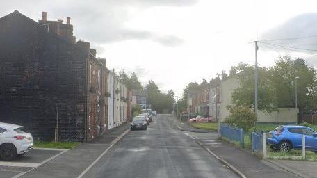 A view of Seddon Street, with terraced houses on either side of the road and parked cars on the left.