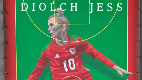 A mural of Jess Fishlock, wearing the Wales number 10 shirt, against a green backdrop.  At the top it reads "Diolch Jess" in white font, meaning thank you Jess in Welsh.