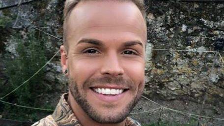 A smiling Olly Marmon looks directly at the camera, in a photograph taken outside