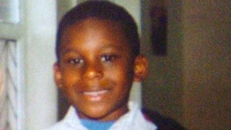 Anthony Walker, aged 10, is smiling at the camera pictured in the family home. He is wearing a white shirt with a blue top underneath. 
