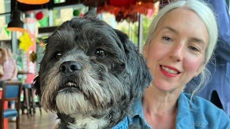 Joanne Jones smiling at the camera, while holding a dog 