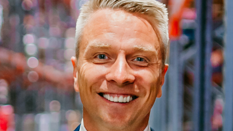 Shows close-up of a fair-haired man with light-coloured hair smiling