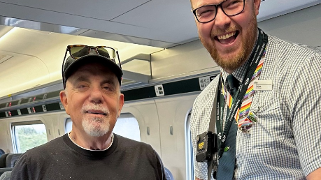 Billy Joel with a ticket conductor on a train to Cardiff