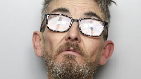A custody image of a man wearing glasses. He has short hair and a beard.