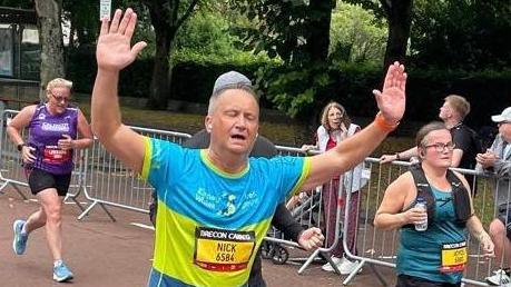 Nick Bowkett holding hands in air as he runs Cardiff 10km 