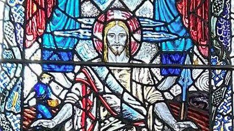 A stained-glass image of Jesus in bright blues and reds
