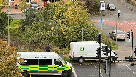 A van has hit the traffic lights. An ambulance is in attendance.