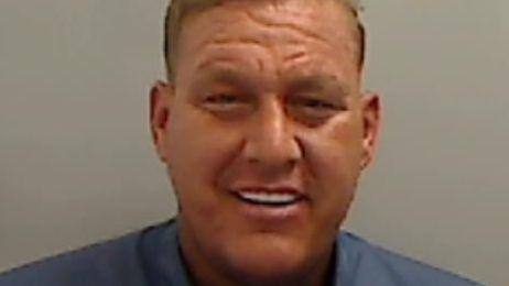 Mugshot of Latham. He is very tanned with straight white teeth and short fair hair.