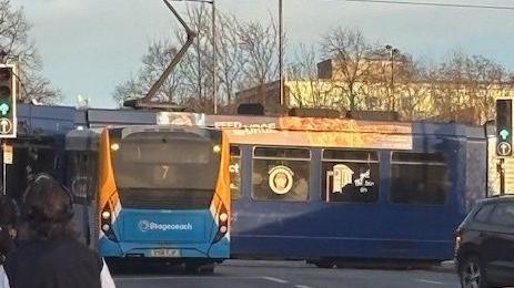 A photo of a blue and orange bus which has crashed into a tram.