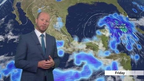 Darren Bett stands in front of a weather map showing a storm developing near Cuba.