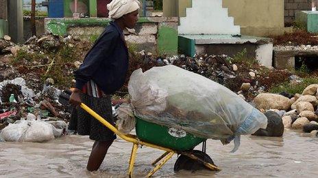 Woman pushing belongings through flooded street