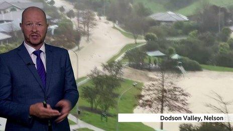 Daren Bett stands in front of a shot of the flooded Dodson Valley in Nelson, New Zealand.