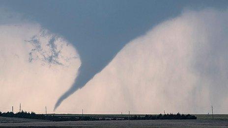 A tornado sweeps across the sky with a field in front