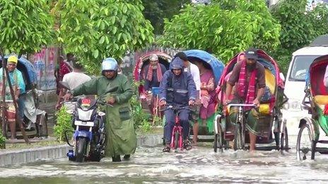 People try to cycle rickshaws through a flooded street in Bangladesh