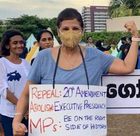 Woman protests, wearing sign and showing strength symbol