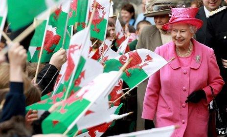 The Queen walks past a crowd of people holding Wales flags