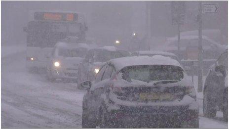 Car covered in snow driving on snow-covered road