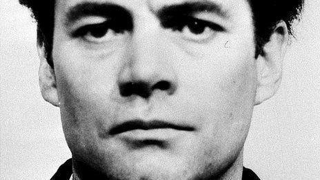 An old black and white photo zoomed in on the face of a man with black hair with a black collar barely visible.  