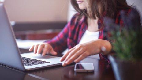 woman on laptop with phone